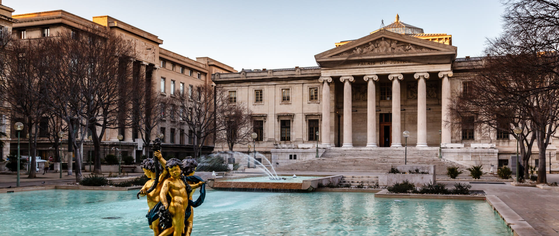 Photographie en couleur d'une perspective du bassin,du parvis et des colonnes de la porte du palais de justice de Marseille